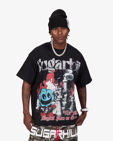 A man wearing a black beanie, a black Sugarhill Gang graphic t-shirt, and camouflage shorts with 'SUGARHILL' printed on the front, standing against a light gray background.