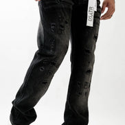 Person wearing black distressed jeans with a visible brand label on a white background