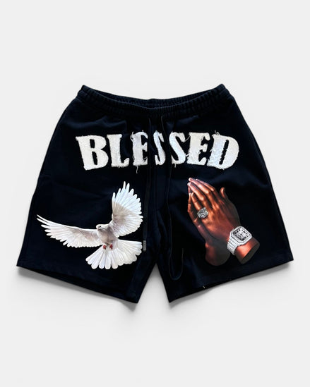 Black shorts with 'BLESSED' text, dove, and praying hands design on a white background
