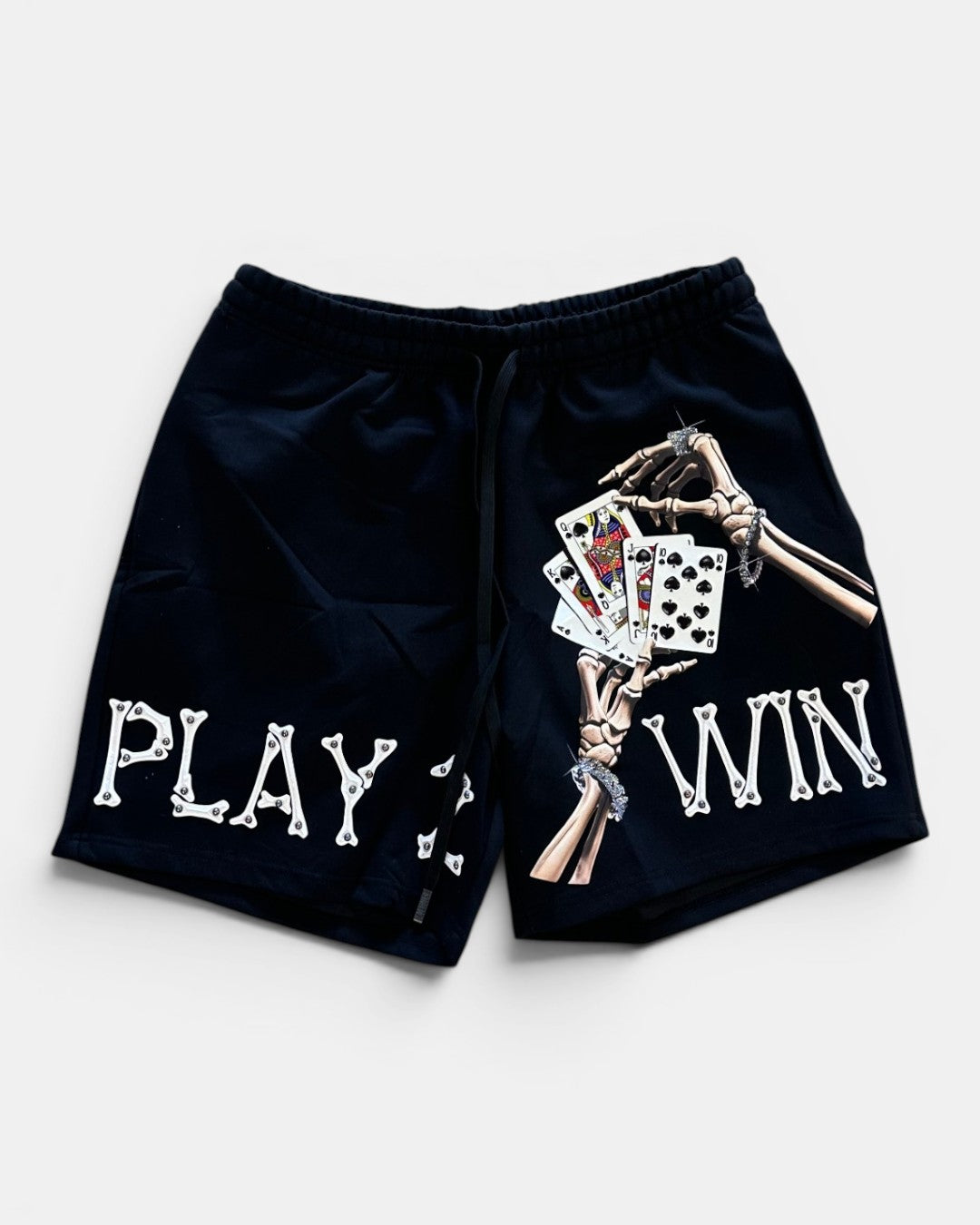 Black shorts with skeleton hand holding cards and text 'PLAY WIN' on a white background