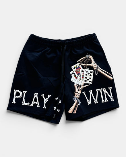 Black shorts with skeleton hand holding cards and text 'PLAY WIN' on a white background