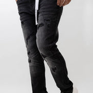 Person wearing black distressed jeans and white sneakers on a white background