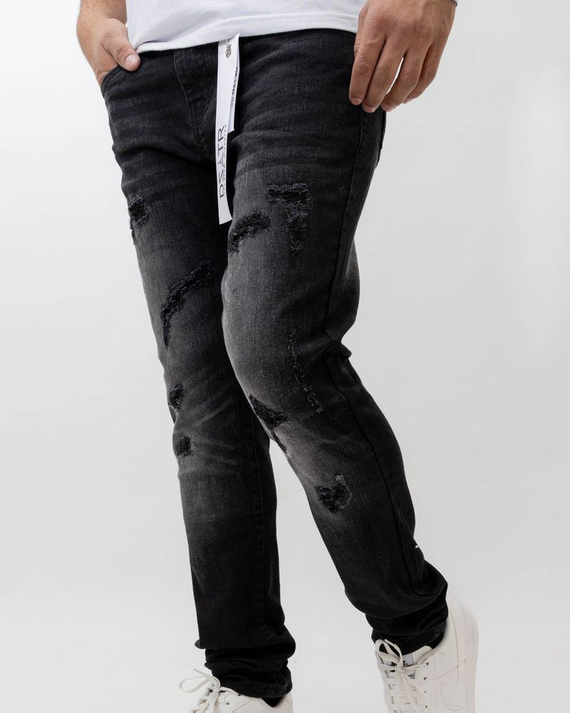 Person wearing black distressed jeans and white sneakers on a white background