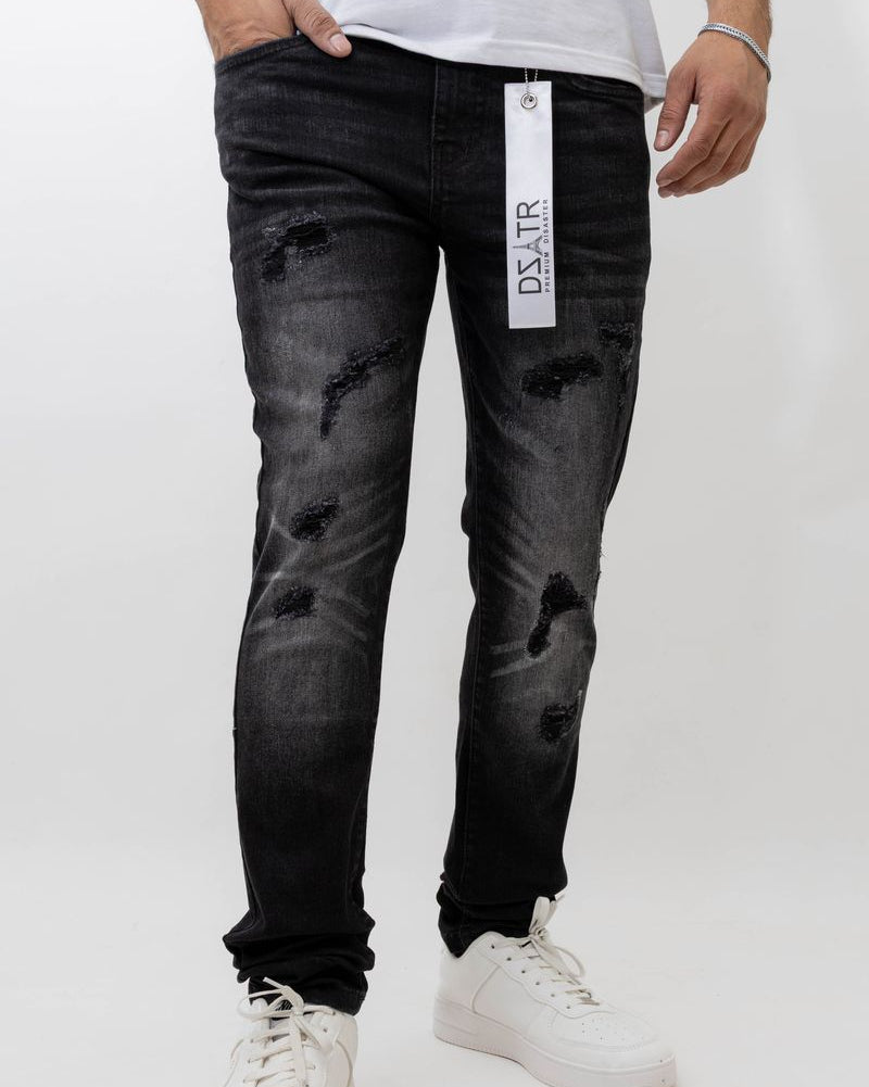 Person wearing black distressed jeans with a visible brand label on a white background