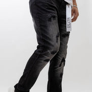 Person wearing black distressed jeans with white sneakers on a white background