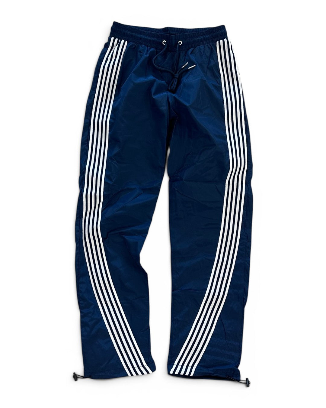Navy blue track pants with white stripes on a white background