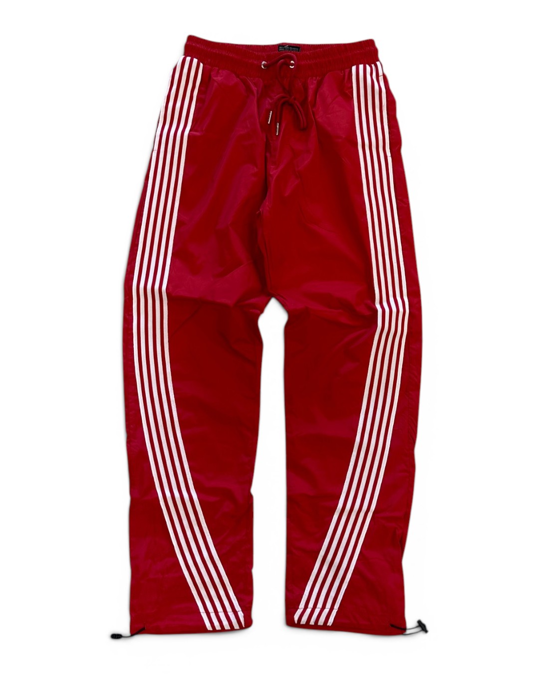 Red track pants with white stripes on a white background