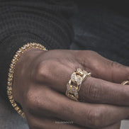 Close-up of a hand wearing the gold studded cuban ring with a blurred background