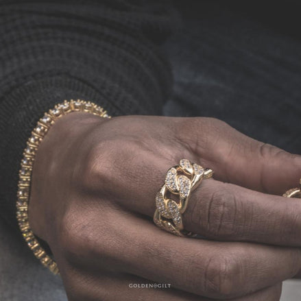 Close-up of a hand wearing the gold studded cuban ring with a blurred background