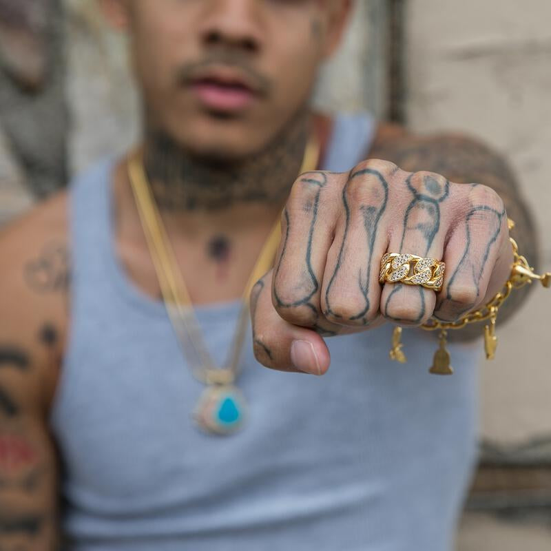 Close-up of a person wearing the gold studded cuban ring with a blurred background
