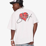 A man shown from the back wearing a white t-shirt with a red and black graphic on the back, paired with light-wash jeans and a black and white cap, against a light gray background.