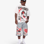A model wearing a white graphic t-shirt with 'SUGARHILL' and a clown print, paired with light-wash denim shorts featuring red and black graphics, white socks, and white sneakers, against a light gray studio background.