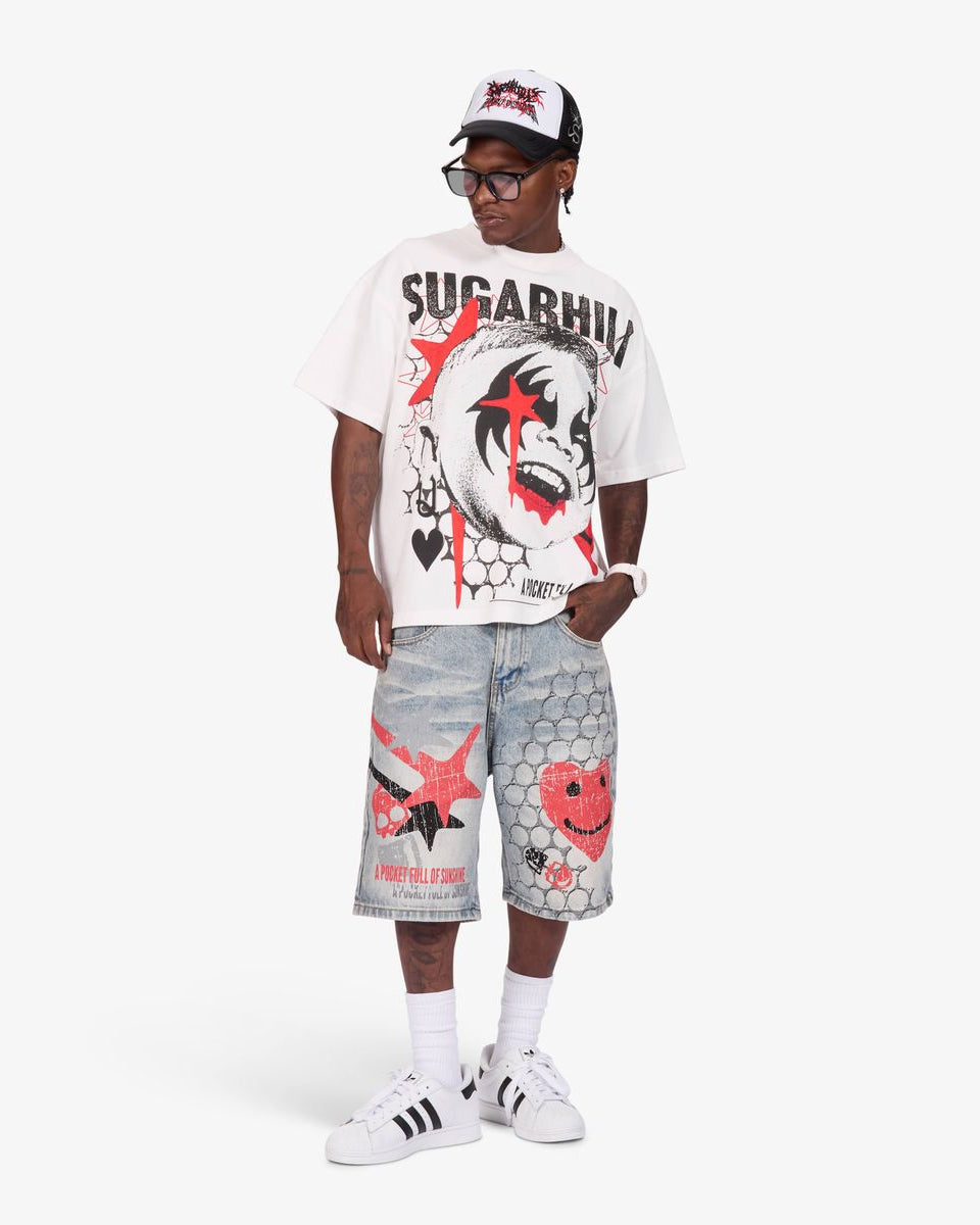 A model wearing a white graphic t-shirt with 'SUGARHILL' and a clown print, paired with light-wash denim shorts featuring red and black graphics, white socks, and white sneakers, against a light gray studio background.