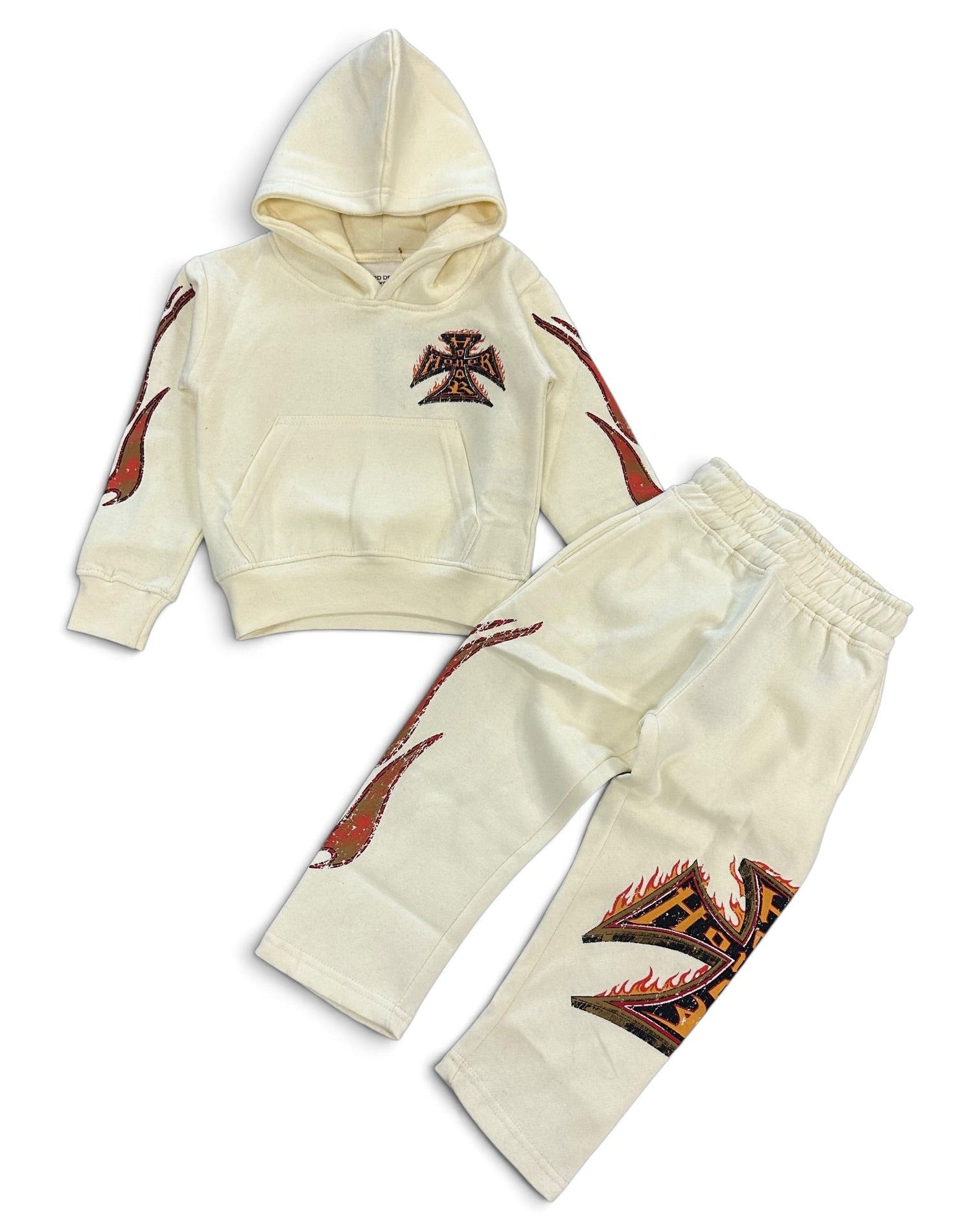 A two-piece baby clothing set consisting of a cream-colored hooded sweatshirt and matching jogger pants, both decorated with red and black flame and cross graphics.