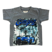 A kids' gray short-sleeve t-shirt featuring a blue and black 'GATTI BOYZ' script logo across the chest, with a graphic of a blue sports car in front of a city scene below.