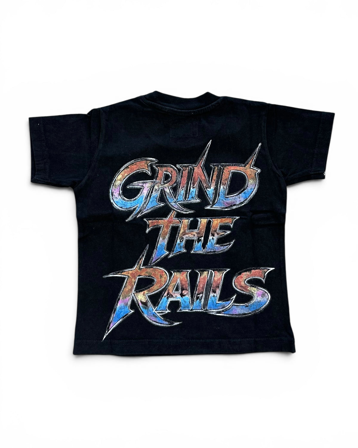A black short-sleeve t-shirt with a large graphic print on the back reading 'GRIND THE RAILS' in a stylized metallic font with blue, orange, and silver colors, shown against a plain white background.
