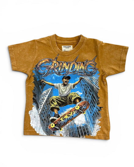 A vintage kids' t-shirt in a washed mustard brown color, featuring a large graphic print of a skateboarder in a city scene with the word 'GRINDING' in stylized lettering.