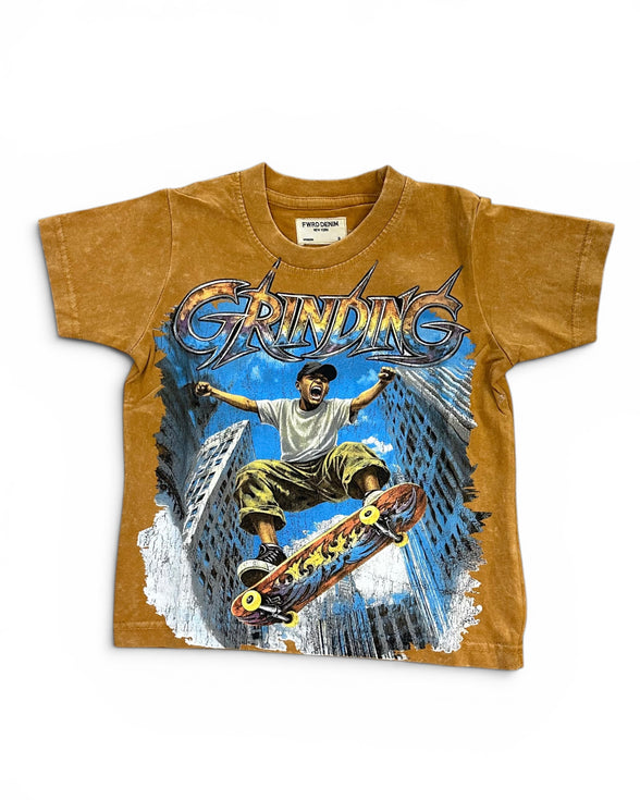 A vintage kids' t-shirt in a washed mustard brown color, featuring a large graphic print of a skateboarder in a city scene with the word 'GRINDING' in stylized lettering.
