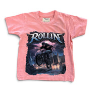 A pink short-sleeve kids' t-shirt featuring a large graphic print of a mountain biker in mid-air with the word 'ROLLIN' in stylized lettering above, set against a plain white background.