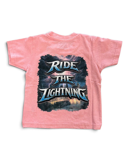 A pink short-sleeve t-shirt with a large graphic print on the back featuring the text 'RIDE THE LIGHTNING' in stylized metallic lettering over a dark stormy sky and lightning scene.