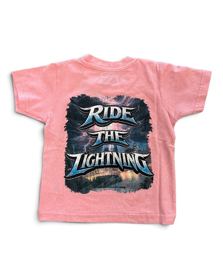 A pink short-sleeve t-shirt with a large graphic print on the back featuring the text 'RIDE THE LIGHTNING' in stylized metallic lettering over a dark stormy sky and lightning scene.