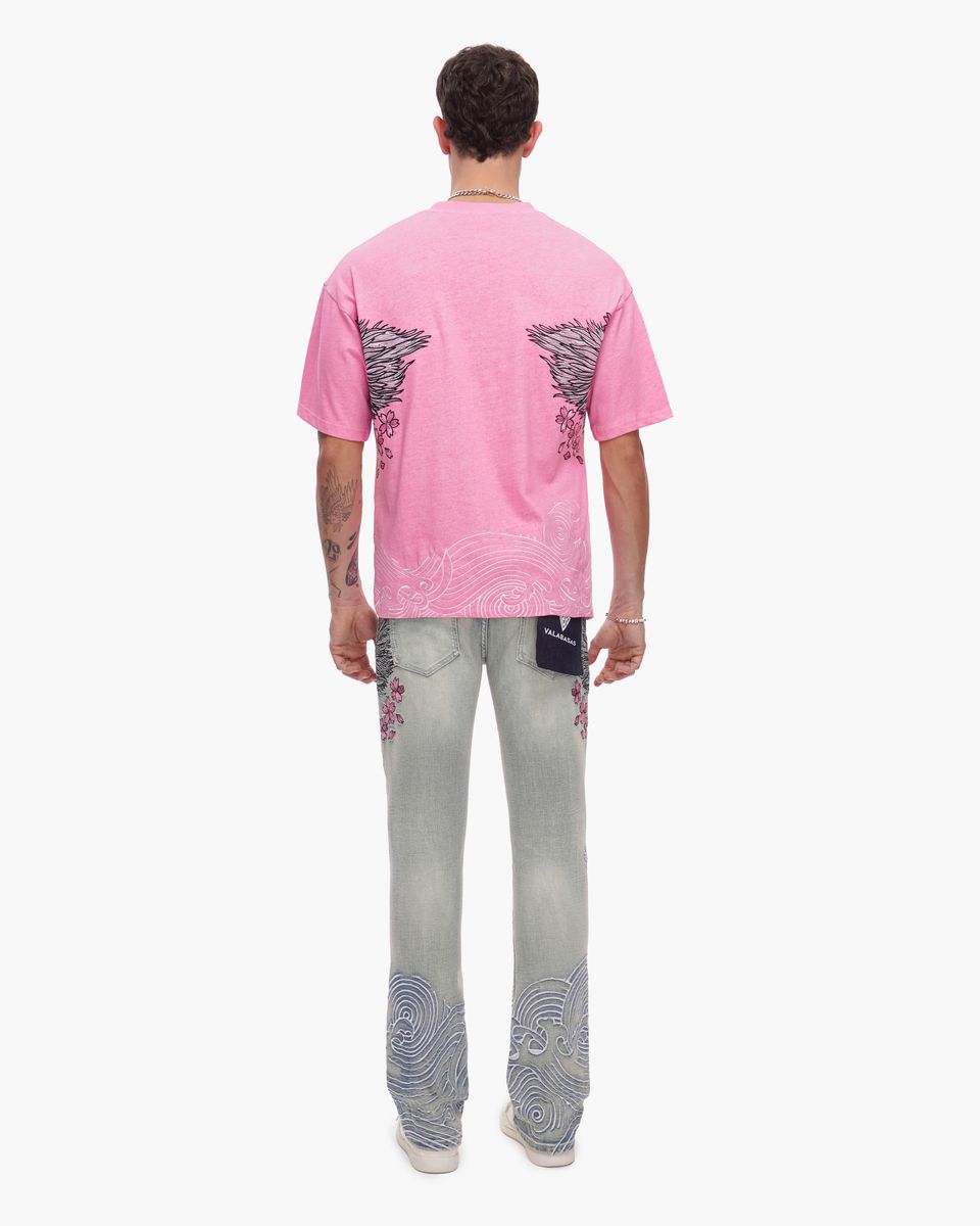 Person wearing a pink t-shirt and light blue jeans with floral designs on a white background