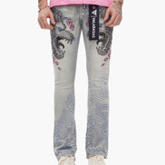 Person wearing gray jeans with intricate designs and a pink top on a white background