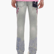 Person wearing light blue jeans with decorative patterns on a white background