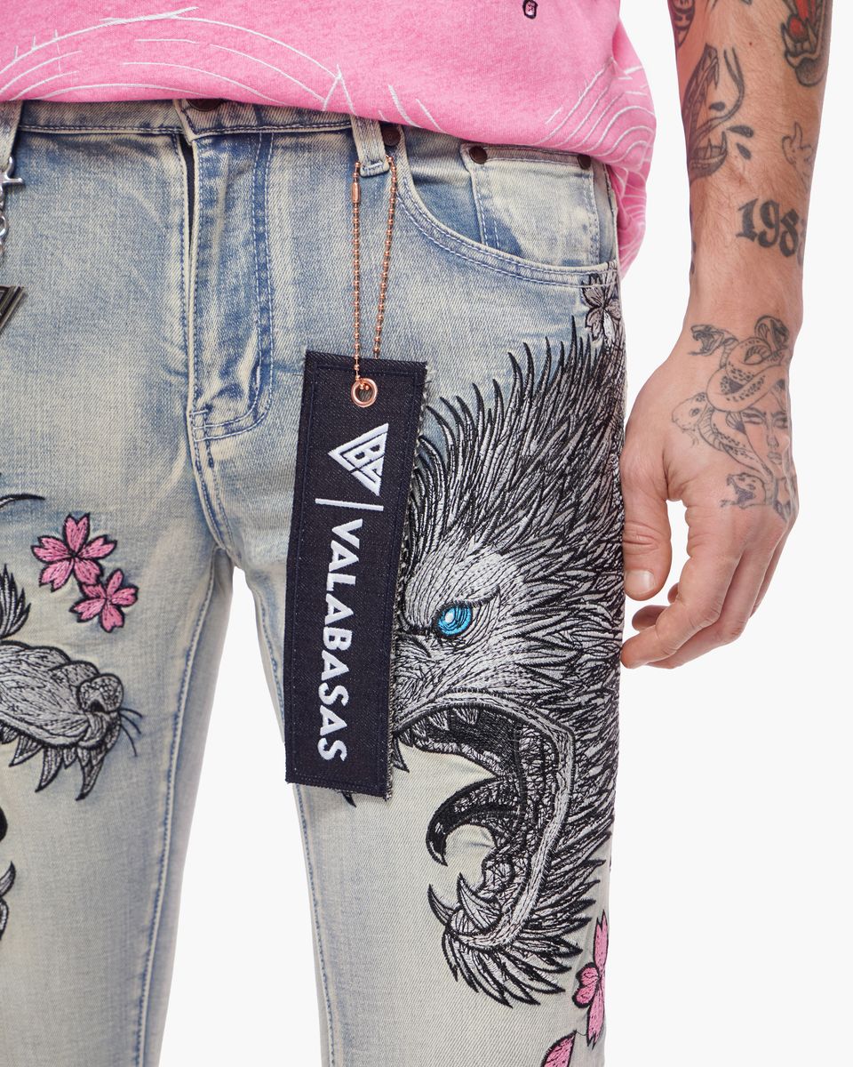 Close-up of jeans with a Valabasas tag and tattooed arm.