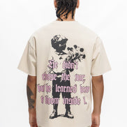Person wearing a beige t-shirt with a graphic design and text on the back, standing against a white background.