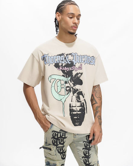 Person wearing a beige t-shirt with graphic design and text, standing against a white background