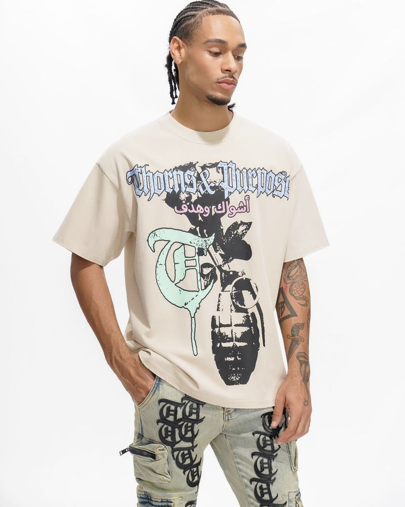 Person wearing a beige t-shirt with graphic design and text, standing against a white background