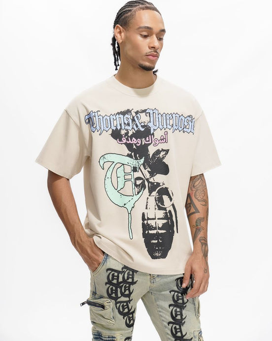 Person wearing a beige t-shirt with graphic design and text, standing against a white background