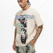Man wearing a beige graphic t-shirt with tattoos on a white background