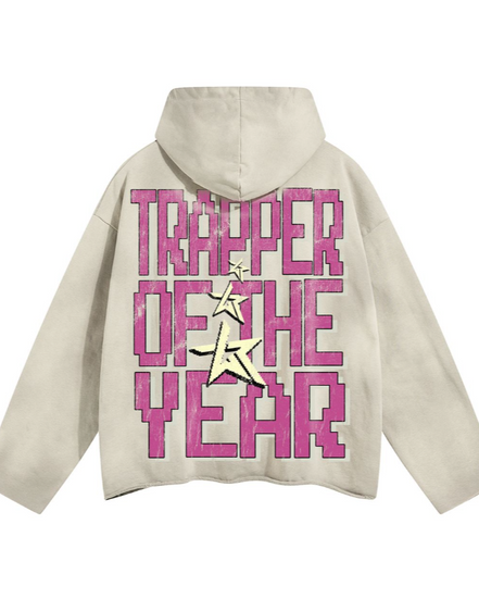 Beige hoodie with pink text 'TRAPPER OF THE YEAR' on a white background
