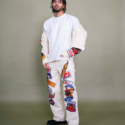 Person wearing a white outfit with colorful patches on a plain background