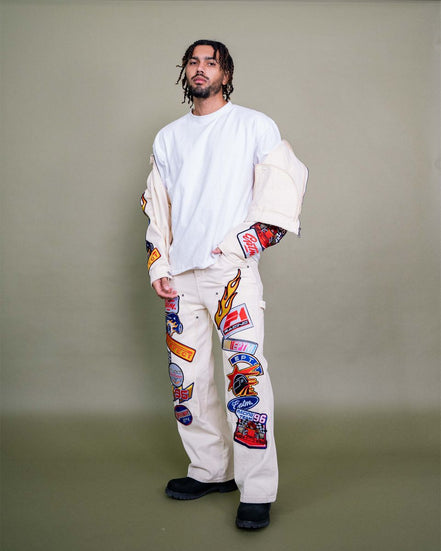 Person wearing a white outfit with colorful patches on a plain background