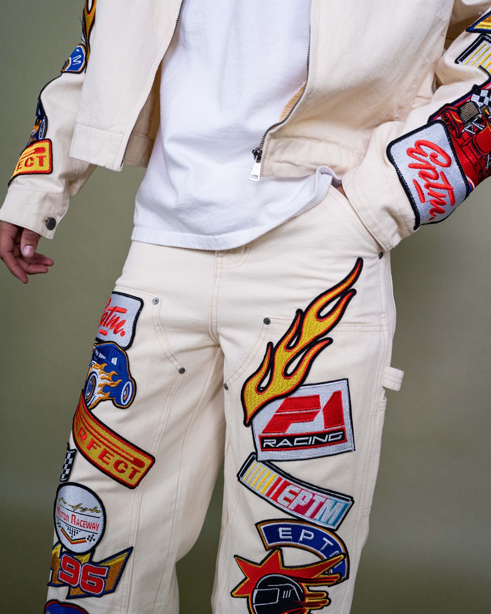 White pants with colorful patches and logos on a neutral background