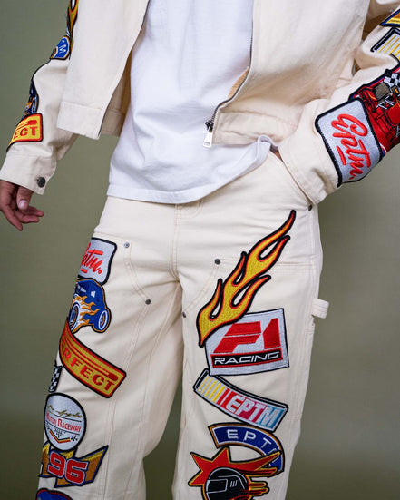 White pants with colorful patches and logos on a neutral background