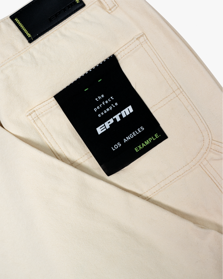 Beige pants with a black label featuring 'EPTM' branding on a white background