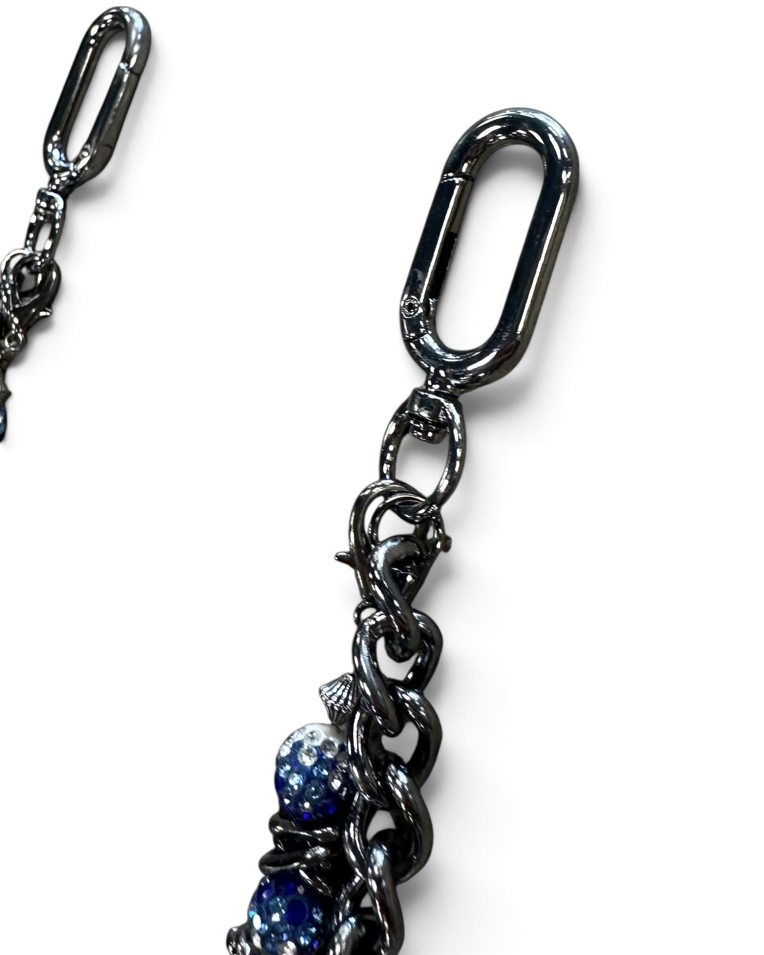 Close-up of a black metal chain accessory with a large carabiner-style clasp and dangling links, including two blue faceted beads near the bottom, on a white background.