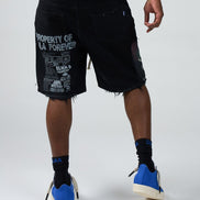 Person wearing black shorts with text, blue sneakers, and black socks on a white background