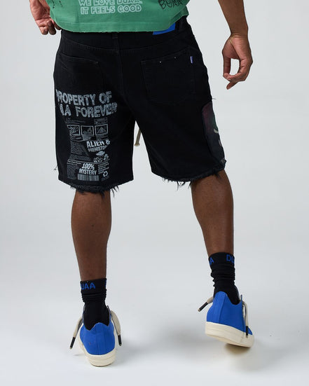 Person wearing black shorts with text, blue sneakers, and black socks on a white background