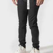 Person wearing black pants with a visible brand label on a white background