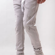 Person wearing light gray distressed jeans and white sneakers on a white background