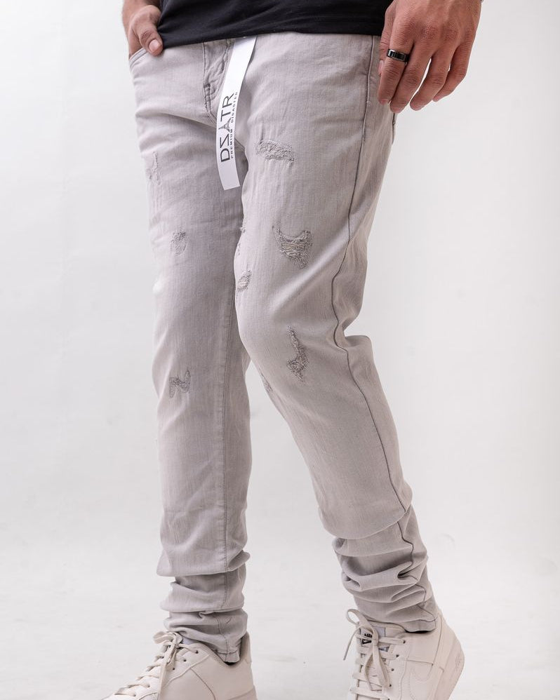Person wearing light gray distressed jeans and white sneakers on a white background