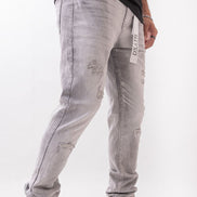 Gray distressed jeans with a brand tag on a white background