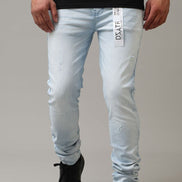 Person wearing light blue jeans with a brand label on a gray background