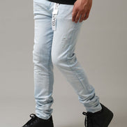 Person wearing light blue jeans and black shoes on a gray background