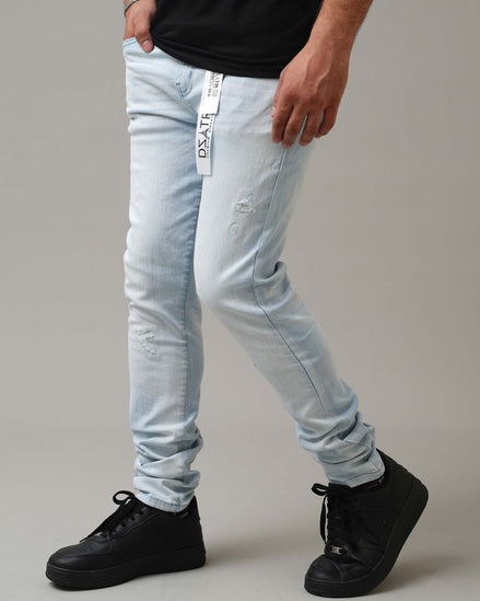 Person wearing light blue jeans and black shoes on a gray background